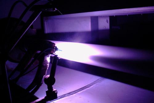 A plasma spray gun coating the outside diameter of a long target.